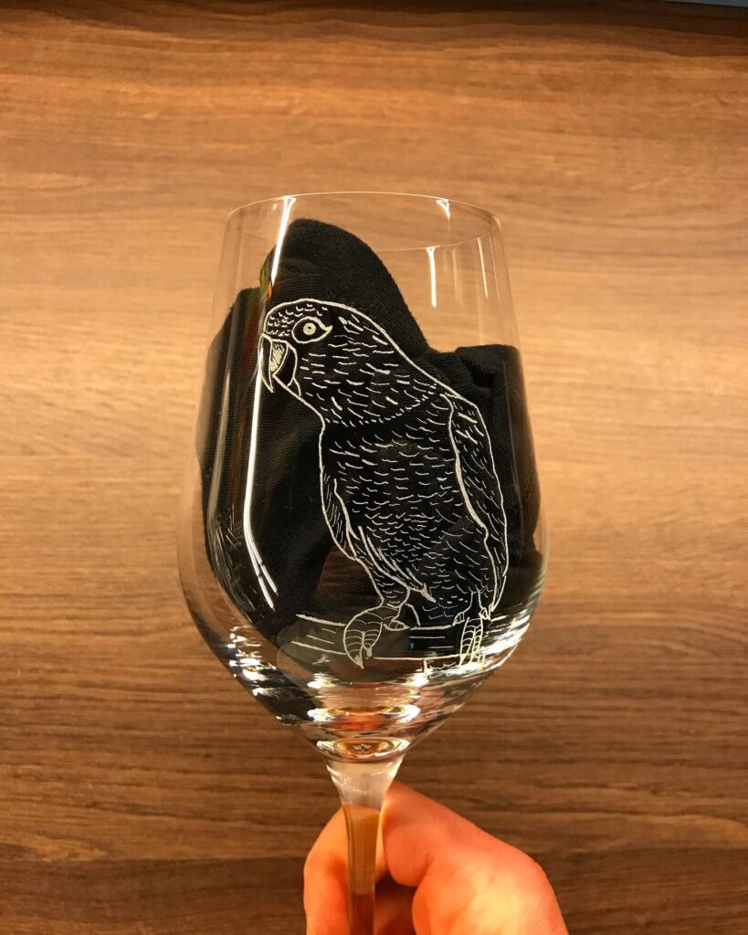 a hand holding a wine glass with a bird on it